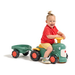 Køretøjstraktor med anhænger til små børn Lille barn leger på grøn ride-on traktor med anhænger