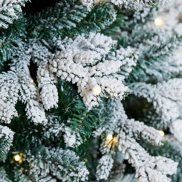 Kunstigt juletræ med sne og LED-lys Nærbillede af kunstigt sneklædt juletræ med LED-lys