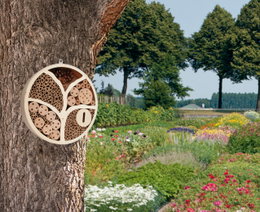 Rundt insekthotel på træ i farverig have