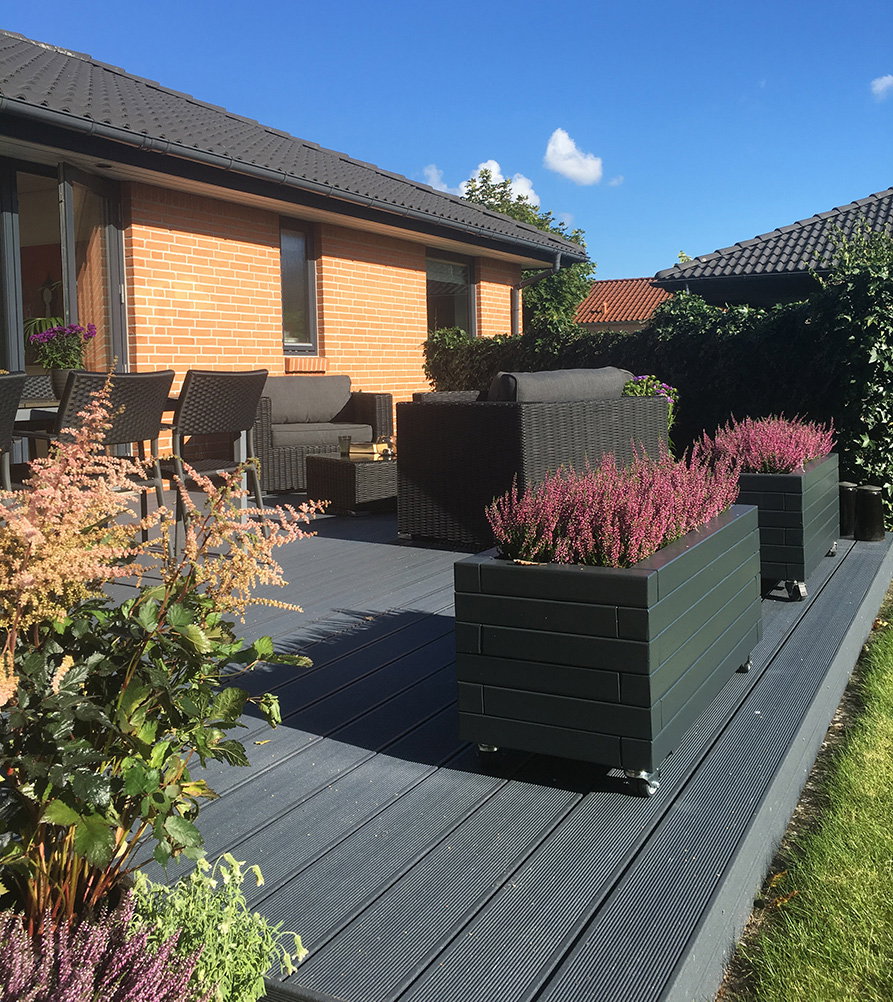 Moderne terrasse med WPC-brædder og loungemøbler Have terrasse i WPC med krukker og loungemøbler
