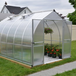 Drivhus Bella 9 m² sølv Palram - Canopia | 2,4 m bred klokkeformet med dobbeltdør, aluminiumsramme & dobbeltvæggede polycarbonatpaneler Drivhus Bella 9 m² sølv fra Palram - Canopia vist med åben dobbeltdør, klokkeformet design (2,4 m bred), galvaniseret stålbase, stærk aluminiumsramme og UV-beskyttede dobbelte polycarbonatpaneler; planter og tomater indeni