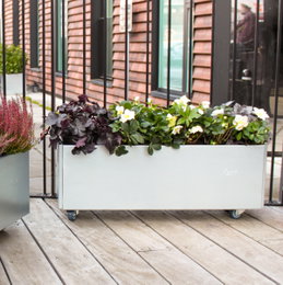 Rektangulær plantekasse på hjul i metal Aflang metal plantekasse på hjul med blomster