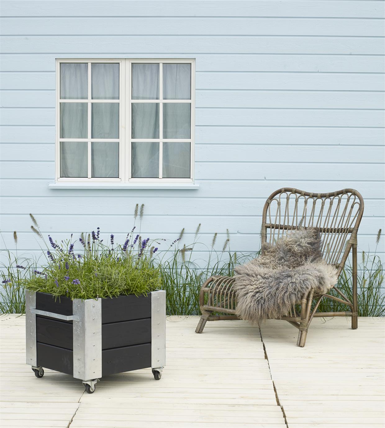 Sort plantekasse på hjul med grønne planter på terrasse