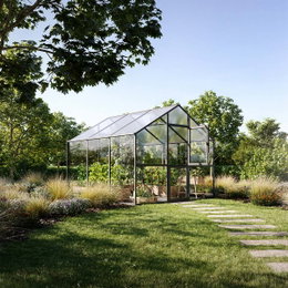 Drivhus i glas til frodig have Moderne glasdrivhus i grøn have med planter