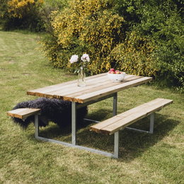 Picnicbord i træ med bænke i grøn have
