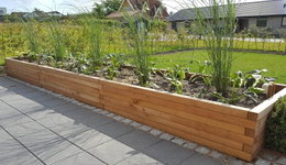 Langt træhøjbed med planter på terrasse