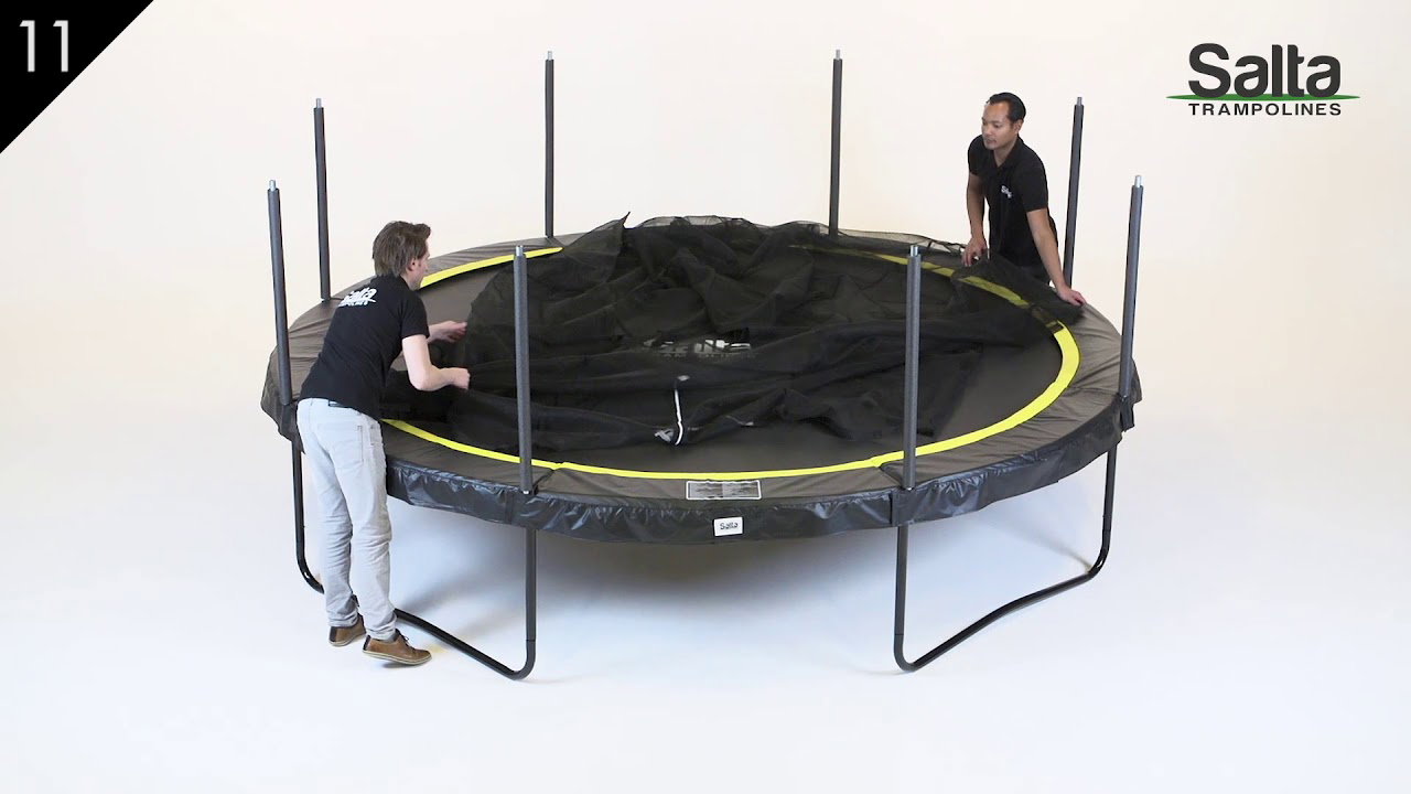Salta Trampolin Comfort Edition Ø366 cm i sort med sikkerhedsnet og polstret kant, U-formede ben og to personer ved opsætning - Salta trampolinen vist fra siden