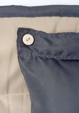Gråt sengetøj med knaplukning i hjørne Detalje af gråt sengetøj med beige knaplukning