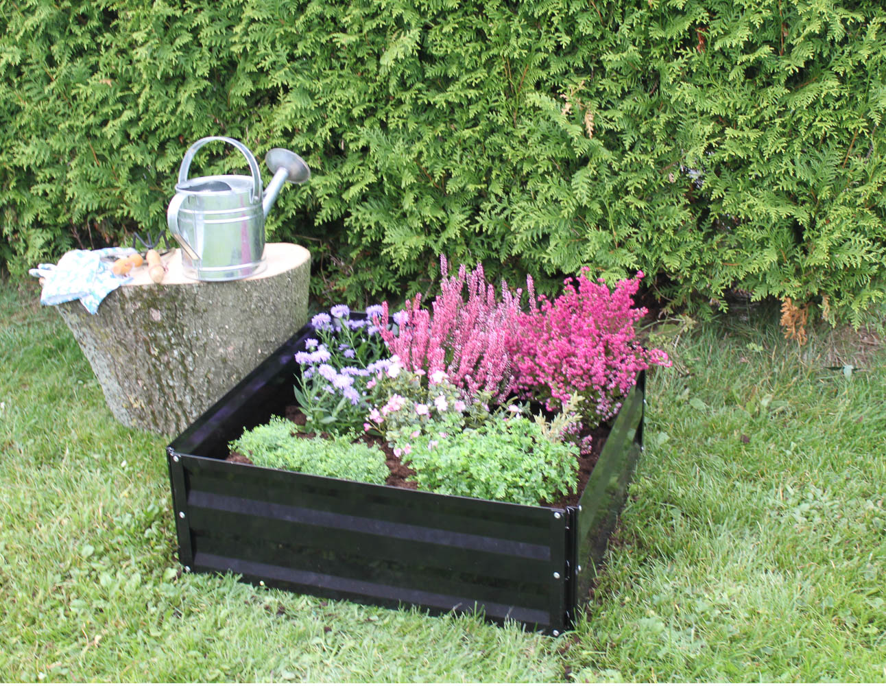 Sort firkantet højbed med blomster i have