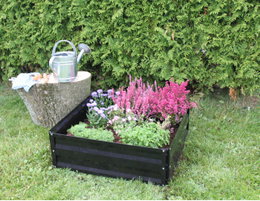Sort firkantet højbed med blomster i have