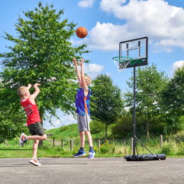 Flytbar basketstander til børn udendørs leg To drenge spiller basket ved flytbar kurv udenfor
