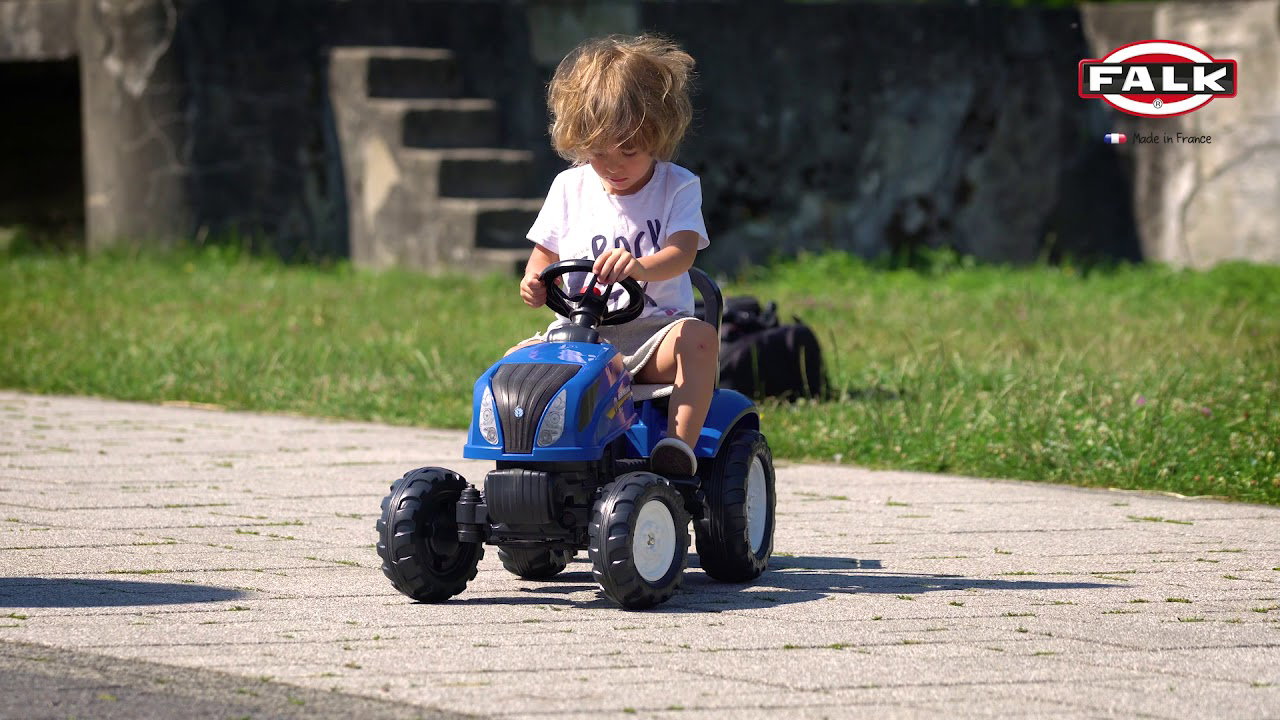 Barn kører blå New Holland pedaltraktor med aftagelig vogn; FALK replika af T6-model, robust pedaltraktor til udendørs leg og udvikling af balance og motoriske færdigheder