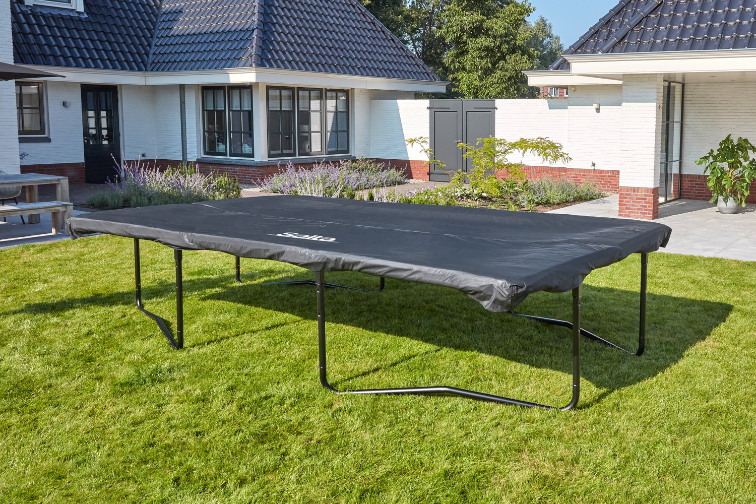 Rektangulær trampolin med sort beskyttelsesovertræk Stor rektangulær trampolin i haven med sort cover