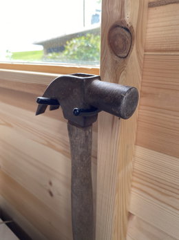Klodset hammer med træskaft i værksted Klodset hammer med træskaft lænet mod trævæg