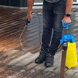 Rengøring af terrasse med tryksprøjte Person rengør træterrasse med gul tryksprøjte