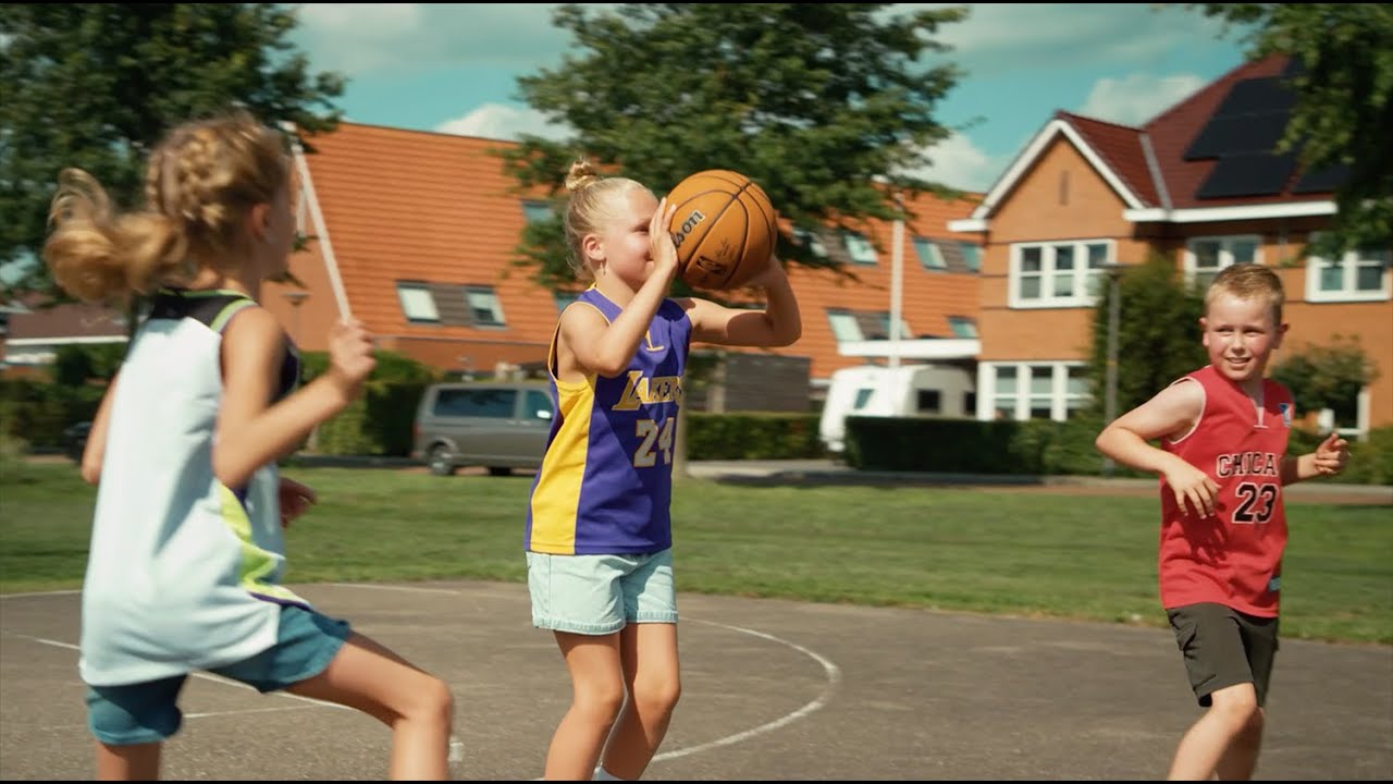 Salta Center basketball stander 128 x 371 x 210 cm – robust galvaniseret stål, justerbar højde, polycarbonat bagplade og dobbelt kompressionskurv Børn spiller basketball udendørs foran en stander, produkt: Salta Center basketballstander 128 x 371 x 210 cm; galvaniseret og mat sort pulverlakeret stål, gennemsigtig polycarbonat bagplade, justerbar højde og dobbelt kompressionskurv for slam dunks