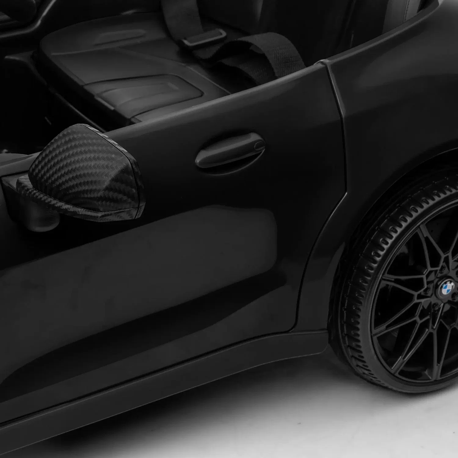 Nærbillede af sort BMW M4 elbil til børn fra NORDIC PLAY Speed med dør, sidespejl, sæde og hjul. Licenseret model med 2 x 10,8V motor, MP3, Bluetooth og fjernbetjening.