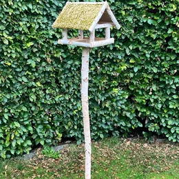 Fuglefoderhus i birketræ på stander med stråtag – HORTUS, 146 cm Fuglefoderhus i ægte birketræ med stråtag på stander (146 cm) fra HORTUS — rummeligt fuglehus hævet på spydstang, beskytter foder mod regn og sne og passer smukt i haven