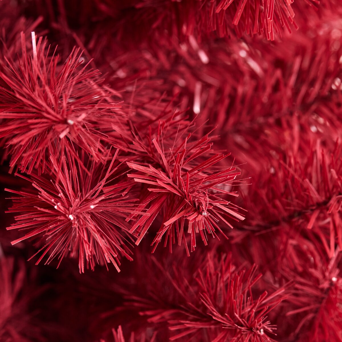 Rød kunstigt juletræ med nåle Nærbillede af rødt kunstigt juletræ