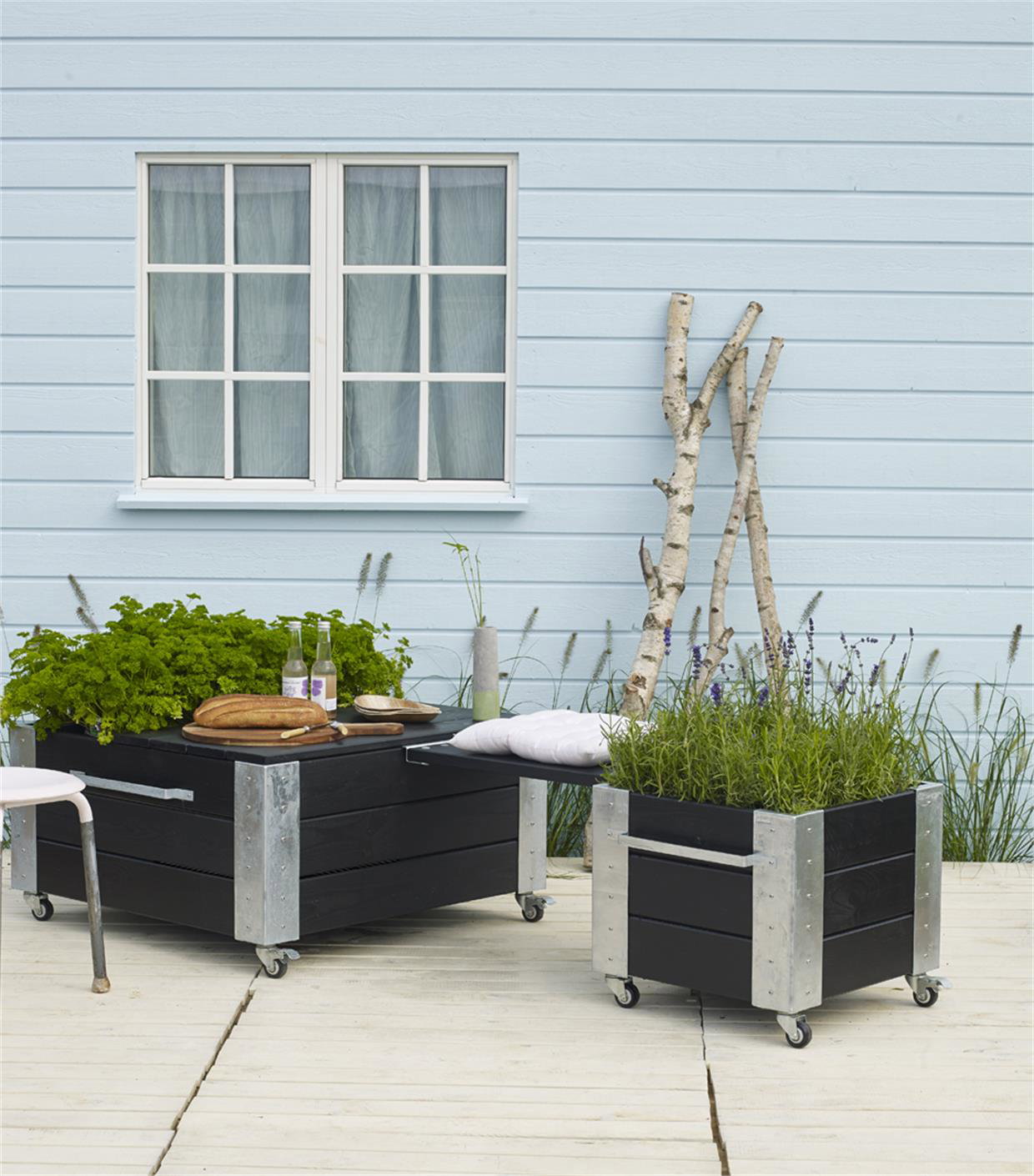 Mobil plantekasse i sort træ til terrasse Terrasse med sorte plantekasser på hjul foran hus
