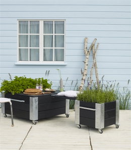 Mobil plantekasse i sort træ til terrasse Terrasse med sorte plantekasser på hjul foran hus