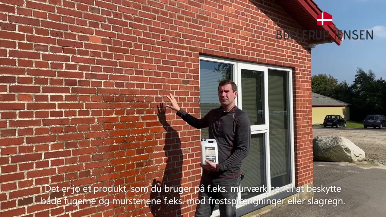 Mand holder 2,5 liter Bollerup Jensen facadeimprægnering foran rød teglmur, viser vandafvisende behandling til mursten, tegl og natursten; 2,5 L rækker op til ca. 25 m²