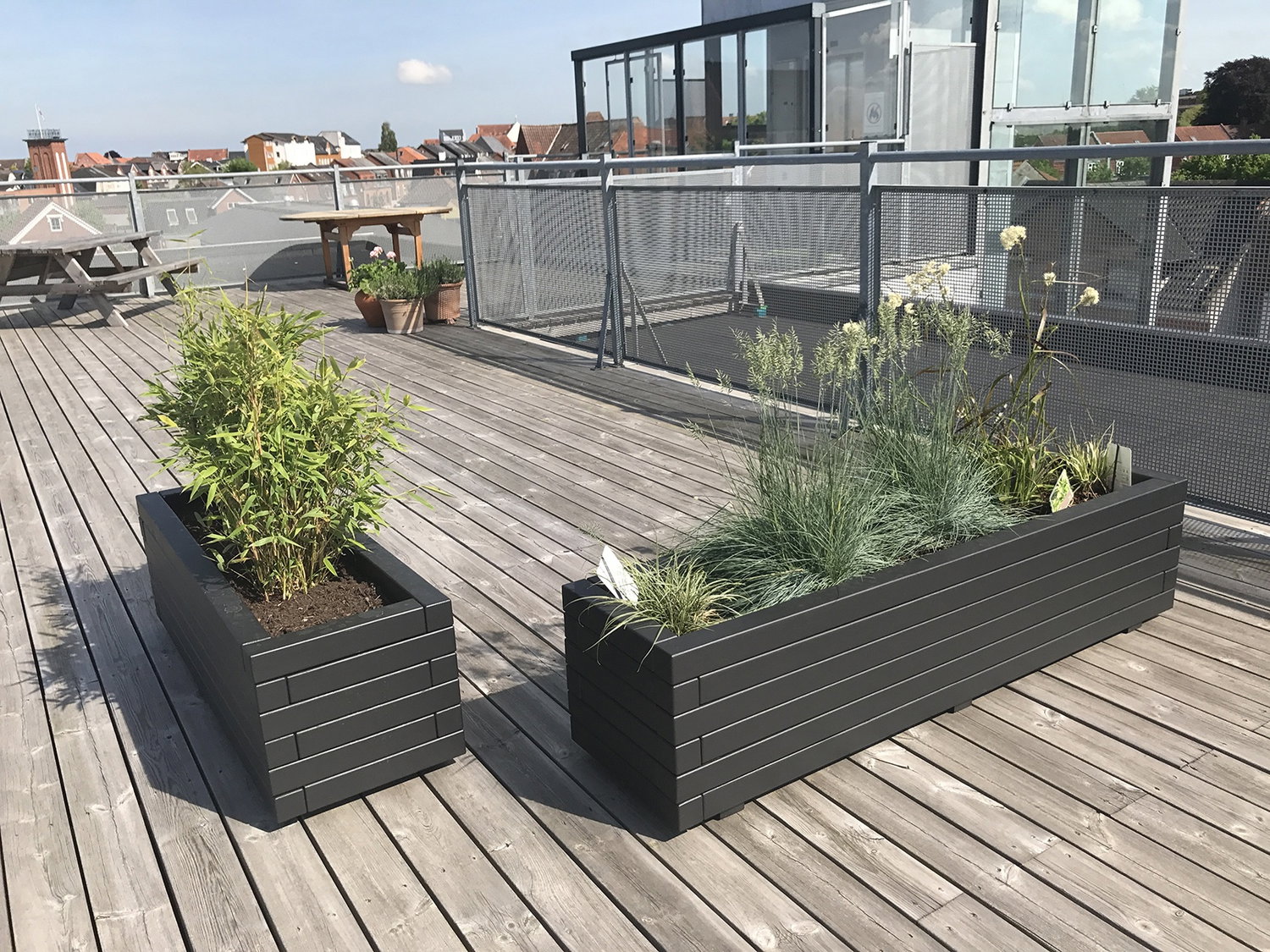 Moderne altankasser i antracitgrå komposit To rektangulære antracitgrå altankasser på træterrasse