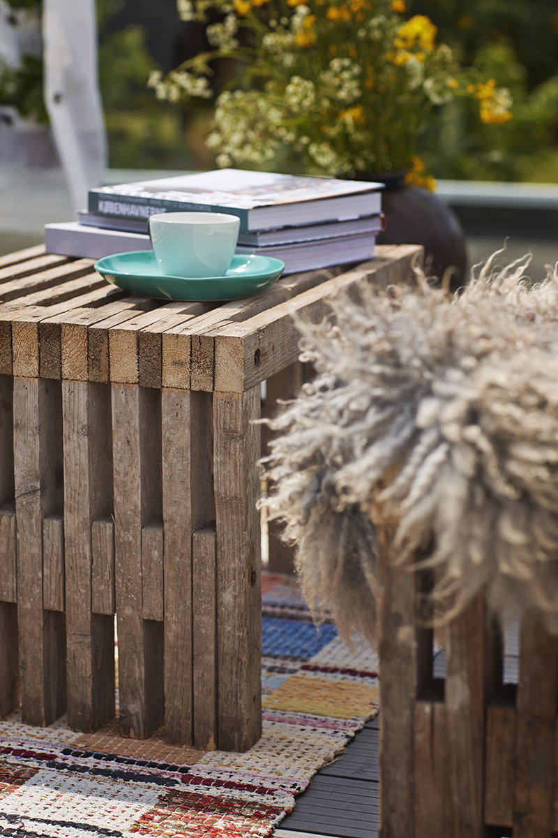 Rustikt sidebord til altan eller terrasse Træsidebord med kop, bøger og farverigt tæppe