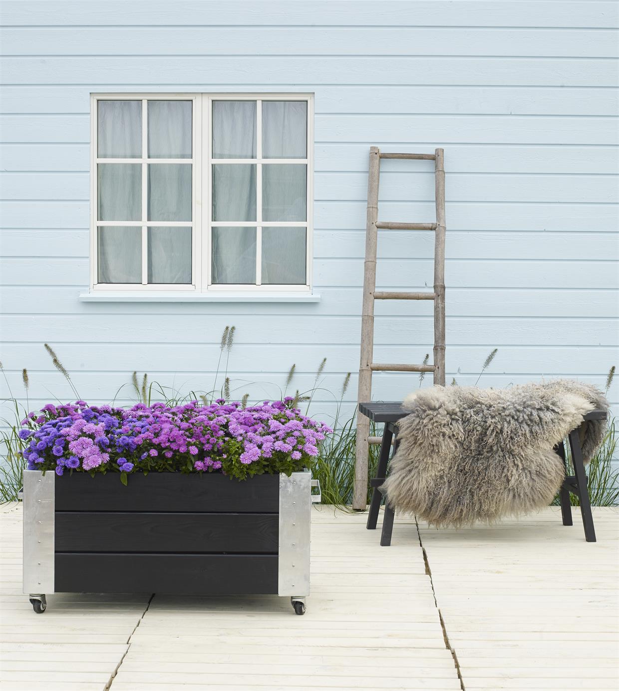 Lys terrasse med sorte møbler og lilla blomsterkasse