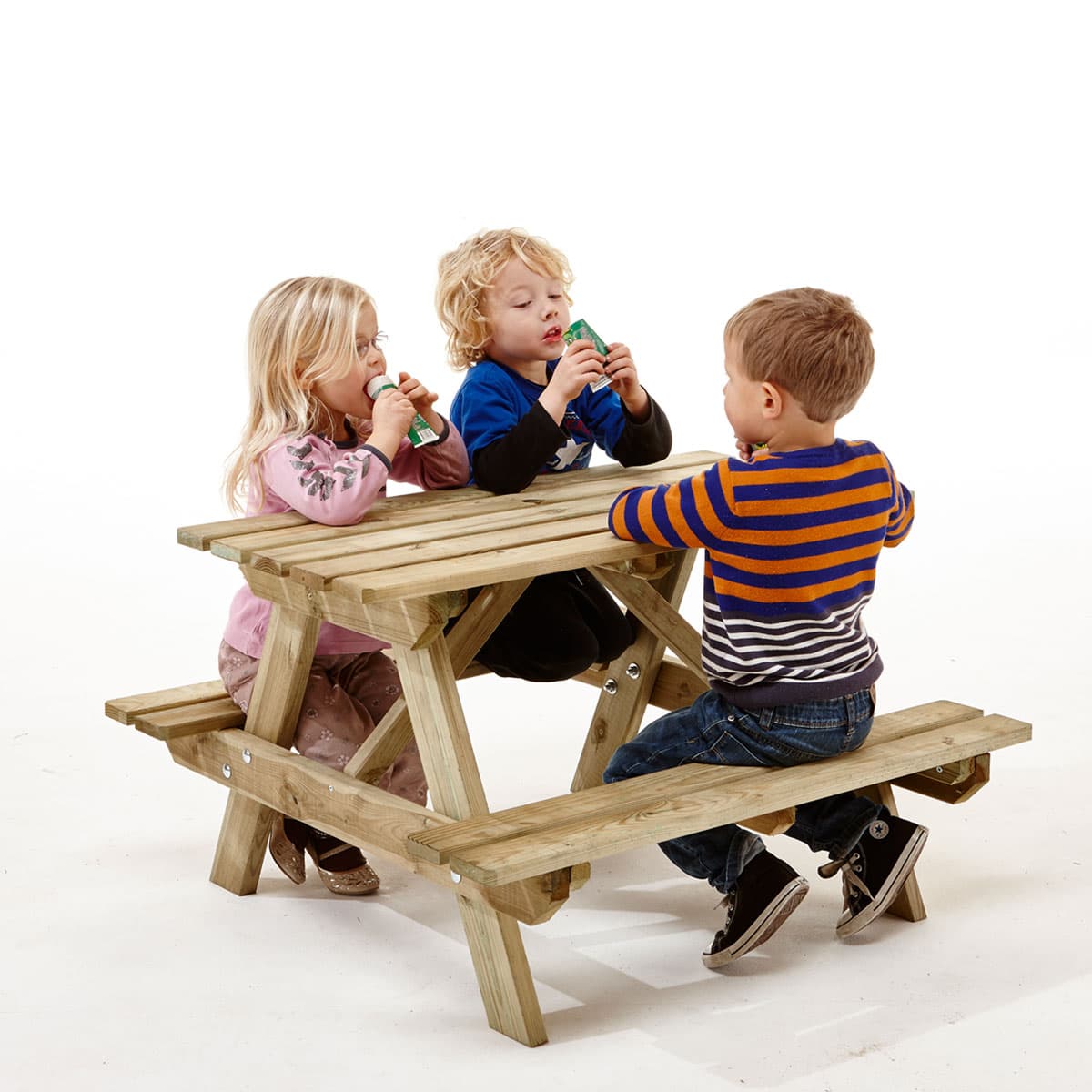 Tre børn sidder ved et lille træ-picnicbord