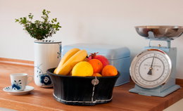 Retro køkkenvægt med frugtkurv Retro køkkenvægt, frugtkurv og porcelæn på bord