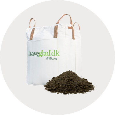 Hvid bigbag med grønne Haveglad.dk-logo og to bærehåndtag ved siden af en bunke løs havejord