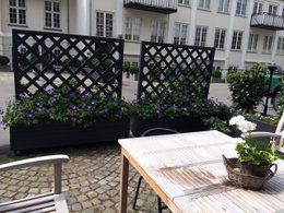 Hyggelig gårdhave med blomster og træmøbler Udendørs gårdhave med blomsterkasser og træbord