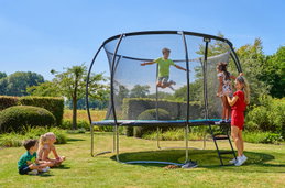 Glade børn hopper på rundt havetrampolin i haven