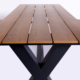 Bord-/bænkesæt X-model i teak nonwood med antracit aluminiumsstel HORTUS – vedligeholdelsesfrit design Nærbillede af Hortus bord-/bænkesæt X-model med teakfarvede nonwood planker monteret på et antracit farvet X-formet aluminiumsstel, holdbart og velegnet til nordisk vejr