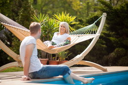 Afslapning i hængekøje ved poolen Kvinde slapper af i hængekøje ved pool med mand