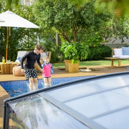 Familiehygge ved udendørs swimmingpool Far og barn leger ved overdækket swimmingpool i have