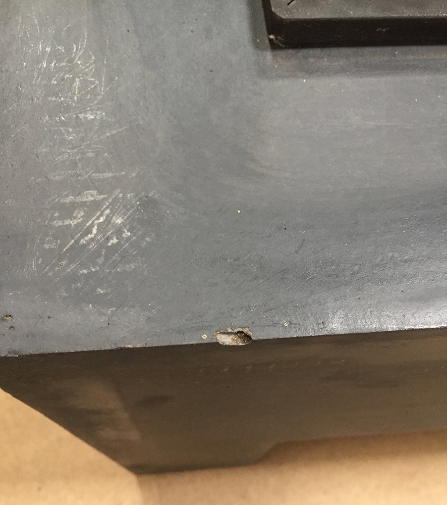 Grå metaloverflade med lille skade på kanten Nærbillede af grå metaloverflade med kantafslag