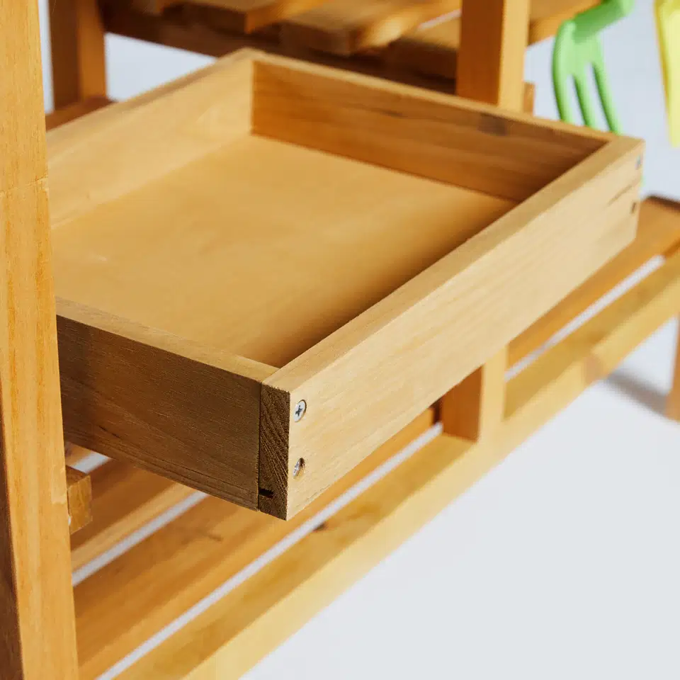 Udekøkken til børn i FSC-godkendt fyrretræ – Nordic Play 77×32×95 cm Detaljebillede af udekøkken i FSC-godkendt fyrretræ fra Nordic Play, viser træskuffe og hylde med naturligt finish. Vejrbestandigt børnekøkken designet til børn fra 3 år, mål 77×32×95 cm.