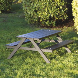 Gråt picnicbord i metal med bænke i grøn have