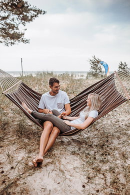 Afslappet par ligger i brun hængekøje på strand