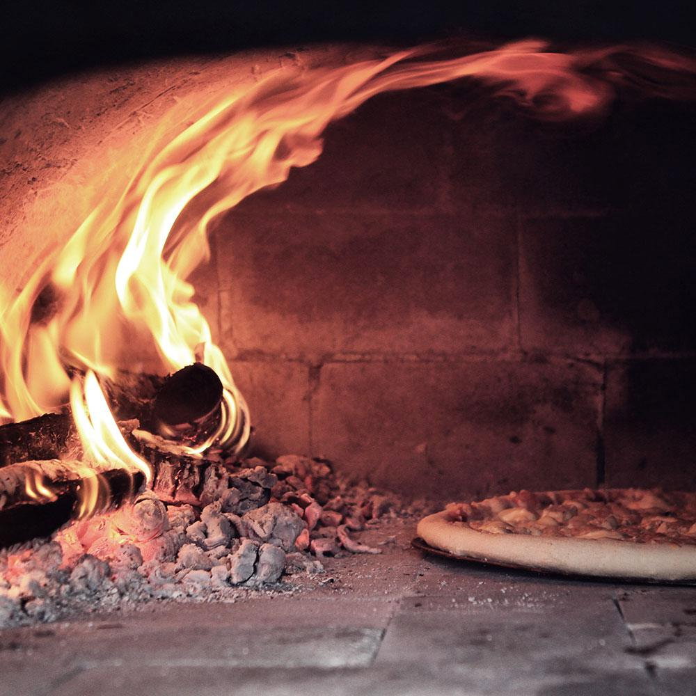 Brændefyret stenovn med pizza på sten