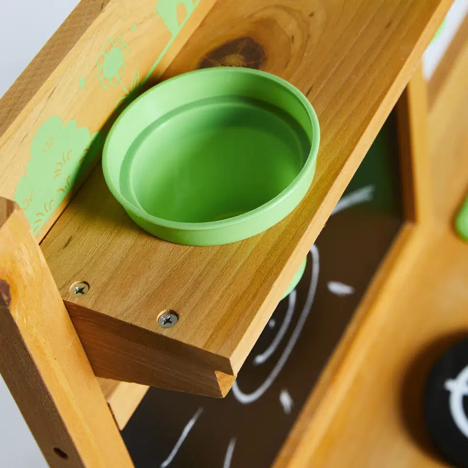 Detaljebillede af Nordic Play udekøkken i FSC-godkendt fyrretræ med grøn plastskål på træhylde; vejrbestandigt udendørskøkken til børn fra 3 år, mål 77×32×95 cm