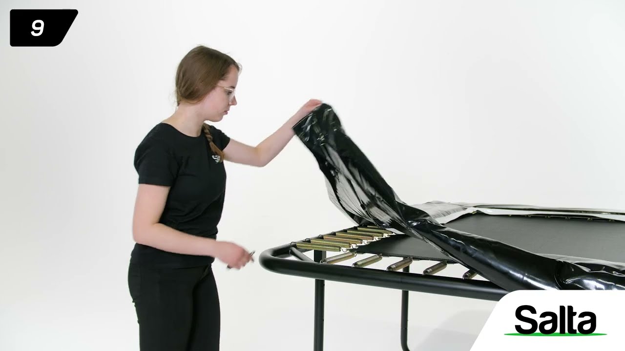 Person fjerner/monterer beskyttelsescover på Salta Trampolin First Class rektangulær 427x244 cm i sort, inkl. stige og sikkerhedsnet