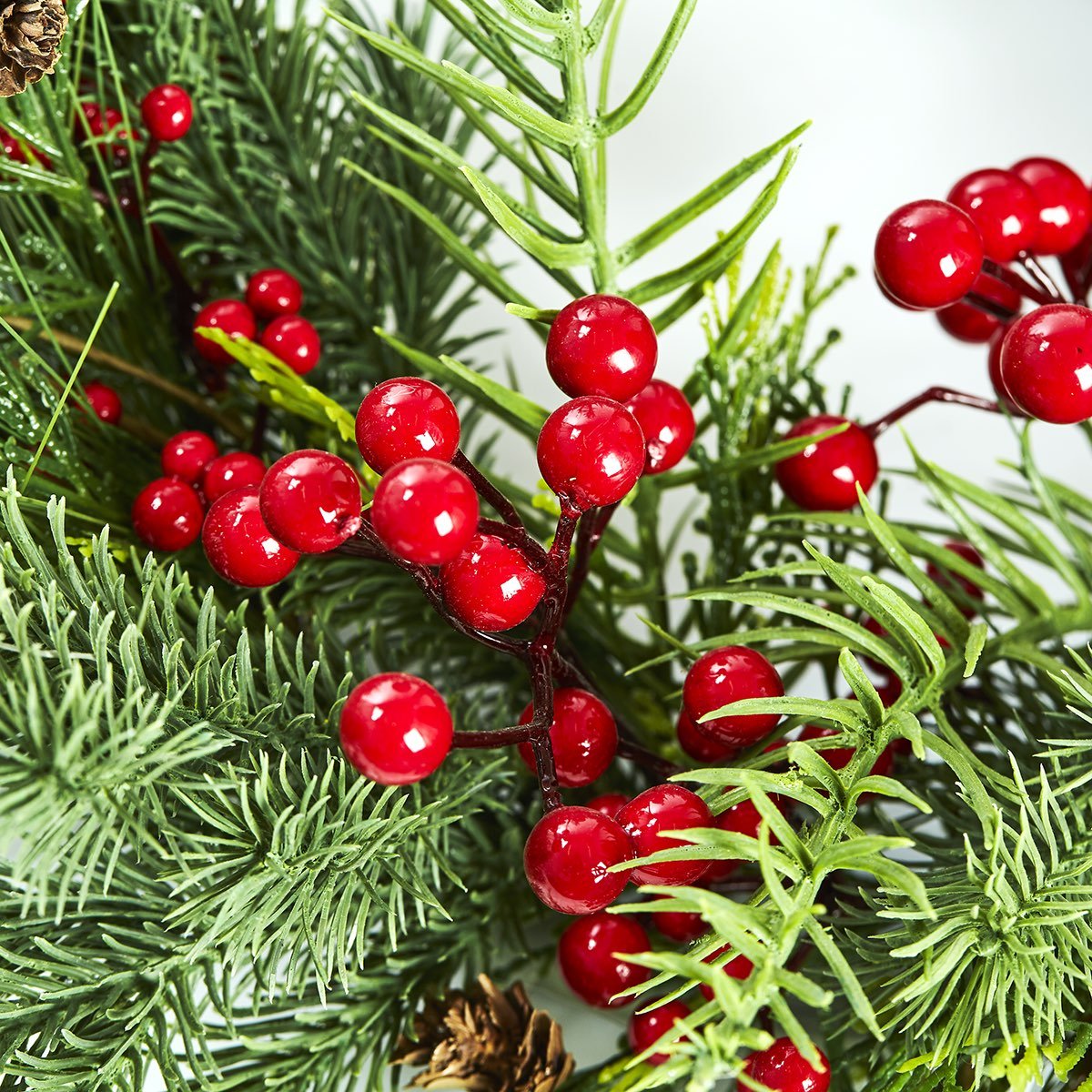 Grøn julegren med røde bær og kogler