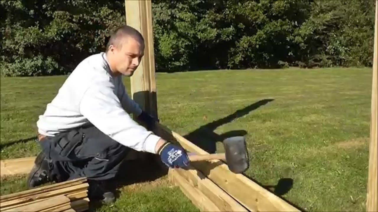 Mellemstolpe til profilhegn 9x9x270 cm fra HORTUS, trykimprægneret NTR‑A fyrretræ H‑stolpe med udfræsning på begge sider, vist under montering på græsplæne