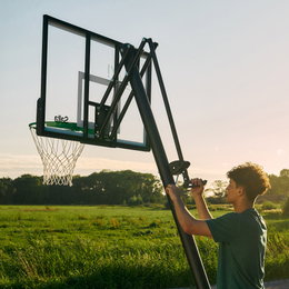 Justerbar basketballkurv til udendørs brug Ung justerer højde på udendørs basketballkurv