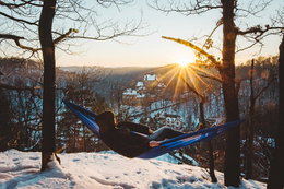 Person slapper af i hængekøje i sne og solnedgang