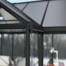 Palram Canopia Triomphe orangeri 16,00 m² antracitgrå – pulverlakeret aluminiumsramme og klare polykarbonatpaneler Detaljebillede af Palram Canopia Triomphe orangeri (16,00 m²) i antracitgrå med pulverlakeret aluminiumsramme, klare akryl- og polykarbonatpaneler og dræningsdetalje på hjørnet