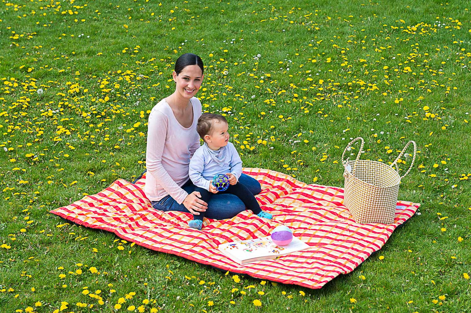 Mor og barn leger på picnictæppe i parken